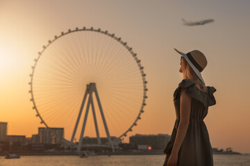 woman enjoying sunset and view to the ferris wheel Ain Dubai. UAE