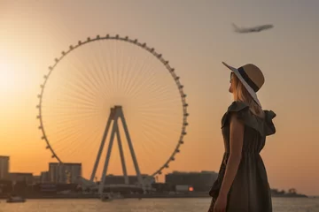 Fotobehang woman enjoying sunset and view to the ferris wheel Ain Dubai. UAE © ronstik