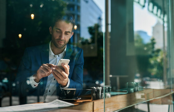 Young businessman using his cellphone at a cafe counter
