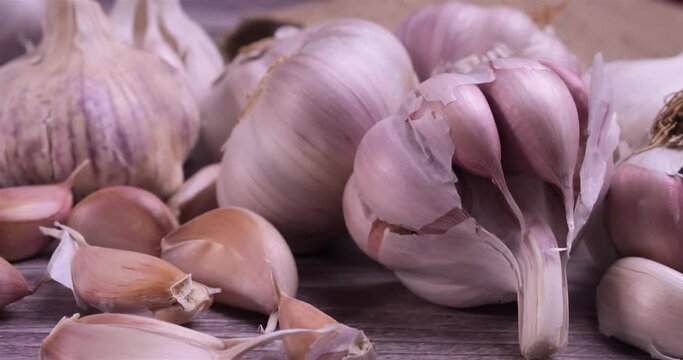 Fresh garlic with intense unique flavor and aroma on wooden background. One of the most popular ingredients of the basic recipes with nutritional properties and health benefits. Dolly shot 4k