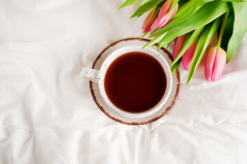 Morning breakfast in bed with coffee cup and pink tulips flowers