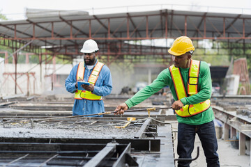 Construction worker uses long steel trowel spreading wet concrete pouring at precast concrete wall...