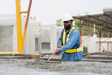 Construction worker uses long steel trowel spreading wet concrete pouring at precast concrete wall...