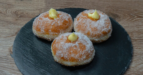 Homemade fried donuts filled with custard and seasoned with a veil of sugar
