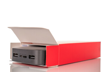 Obraz premium One black portable power bank charger with red paper box, close-up isolated on white background.