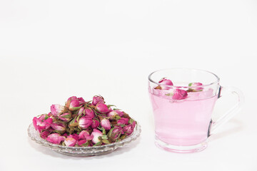 Pink tea in a clear glass mug and dry little pink rose buds