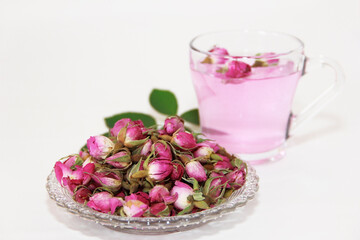 Pink tea in a clear glass mug and dry little pink rose buds