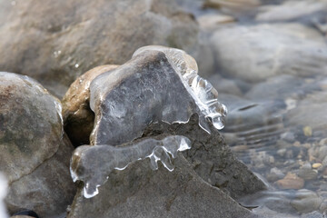 Springtime nature image of the last remaining shards of ice clinging to the tops of the rocks as the river melts.