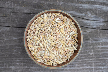 Bowl of wheat grains on wooden board