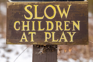 Weathered wood sign on building, Slow Children at Play..  