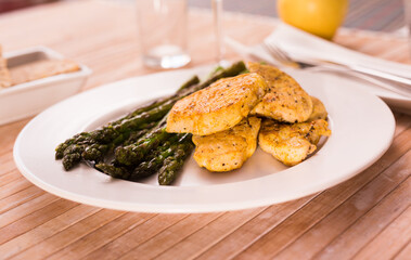 cooked dish. Chicken nuggets with green asparagus on plate