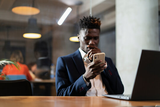 Portrait of successful businessman in office. Young smiling man using the phone.