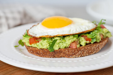 Toast with guacamole and avocado in a white plate on the table