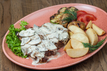 Baked meat with mushroom sauce and potatoes on a plate