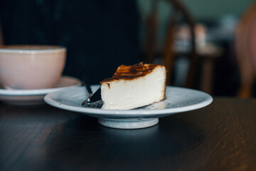 Classic Basque cheesecake on a plate. A piece of delicious cake on a white plate, served with a dessert fork
