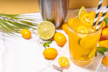 Kumquat lemonade drink. Non-alcohol citrus cocktail with kumquat fruit slices, lime, mint and crushed ice, on sunny background copy space