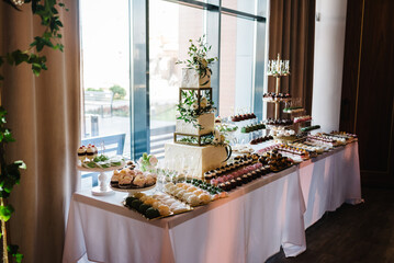 Delicious wedding reception. Birthday Cake on a background party. Candy bar with wedding cake with flowers for banquet. Celebration concept. Trendy Cake.Table with sweets, candies, dessert.