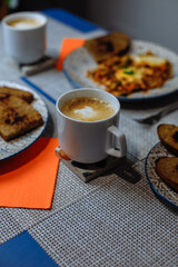 Breakfast, scrambled eggs with toast and coffee in a white cup