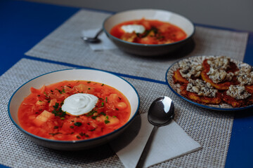 Two plates of red borscht with dumplings on the table