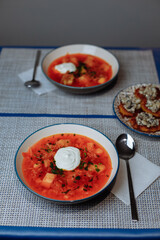 Two plates of red borscht with dumplings on the table