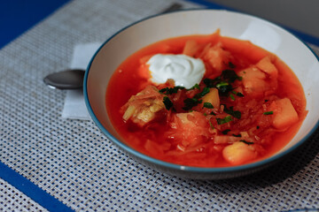 Two plates of red borscht with dumplings on the table