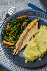 Potatoes with fish and sauce and vegetables on the table