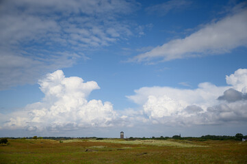 Fototapeta na wymiar Dutch field landscape with clouds and water tower of Ter Heijde.
