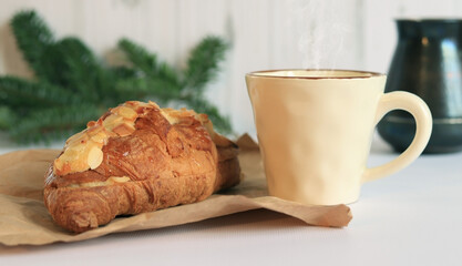 Coffee with croissants. Hot coffee and French croissant on a light background. Breakfast or lunch in a cafe, fir branches on a blurred background