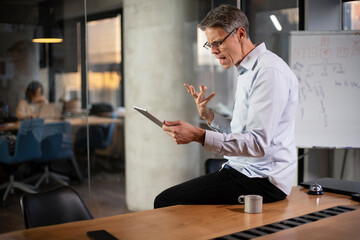 Fototapeta premium Portrait of businessman in office. Man using digital tablet. Businessman having video call