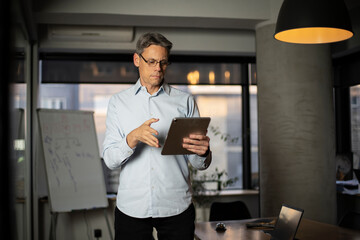 Naklejka na ściany i meble Portrait of businessman in office. Man using digital tablet. Businessman having video call