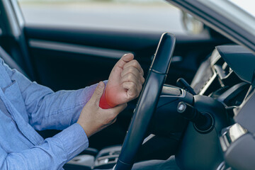 Man hurts wrist while driving The left hand with the red dot grasps the right wrist while holding...