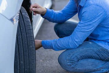 Man is changing a broken tire on the road with a screwdriver wrench.