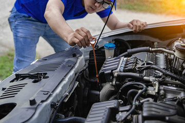 Young man checking and maintaining the quality of engine oil in his car Car repair and maintenance,...