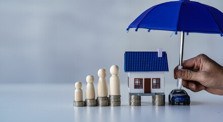 Blue umbrellas on houses and small cars, stacks of money, wooden dummy, protection, insurance industry, real estate Property security, protection concept under blue umbrella isolated on white © ArLawKa