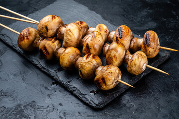 Grilled mushroom skewers, dark textured background.