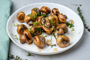 Roasted mushrooms in a white plate with garlic and herbs.