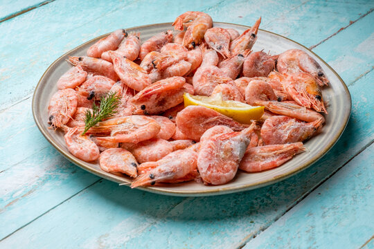 Plate with frozen shrimp on a wooden background.