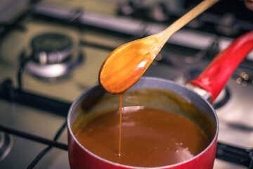 Close-up of a chef's hand-cooking creme caramel sauce 
