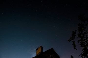 photo of a roof illuminated by moonlight and the starry sky above it. Stars, Roof,Dream. Atmospheric photography of the Starry Sky. take a walk on the roofs and admire the stars. soft focus.copy space