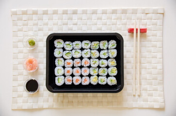 Maki sushi on a bamboo placemat with chop sticks, soya, fresh ginger and wasabi