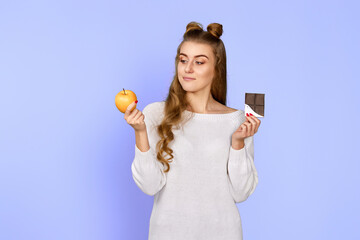 woman in sweater showing sweet chocolate bar and fresh apple