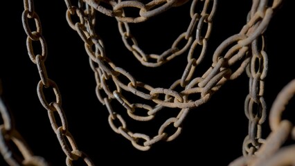 Rusty metal old chain dangling in dark indoor space. Close up of the links of an aged iron chain covered with corrosion and dust. Rough damaged metal structure. Grunge. Strong uneven metal connections
