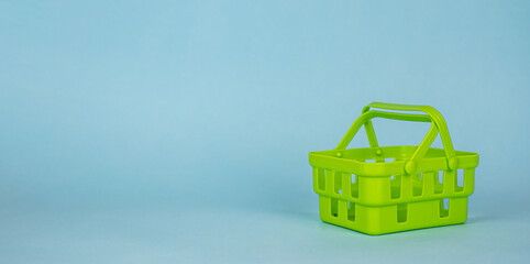 An empty green shopping basket on a blue background. Banner, copy space for text. The concept of online shopping, sales, stores