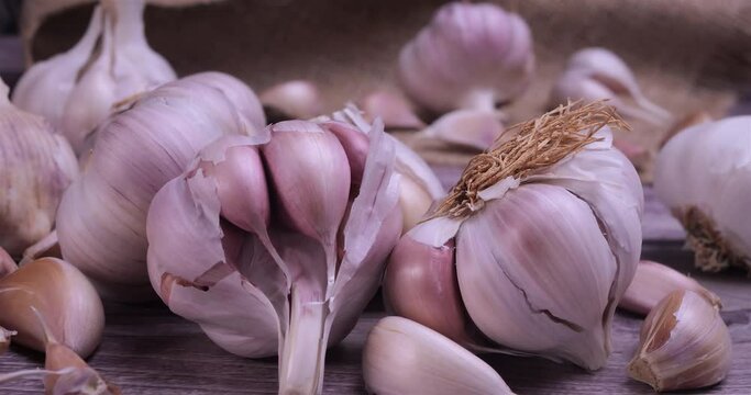 Fresh garlic with intense unique flavor and aroma on wooden background. One of the most popular ingredients of the basic recipes with nutritional properties and health benefits. Dolly shot 4k