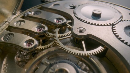 Internal working mechanism of an antique pocket watch. Reverse side of a pocket watch with an open clockwork. Screws, spring, gears and cogwheels of an old clock. Disassembled pocketwatch. Macro shot.