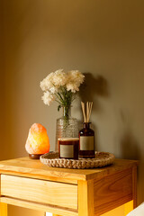 aroma diffuser and candle on wooden table with salt lamp and vase
