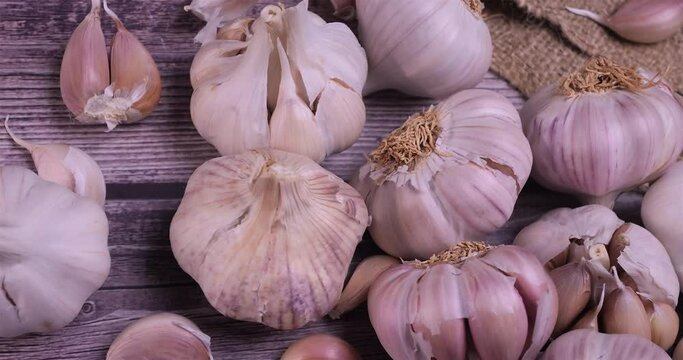 Fresh garlic with intense unique flavor and aroma on wooden background. One of the most popular ingredients of the basic recipes with nutritional properties and health benefits. Dolly shot 4k