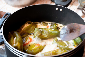 Traditional homemade bell pepper stuffed with cheese and cream sauce in a cooking pot, latin food