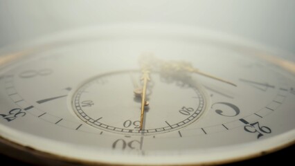 Antique pocket watch with a white dial and gold hands in bright light. The face of an old clock...