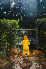 A child in a yellow jumpsuit and hat walks in a park with a fountain at Villa Durazzo in Genoa, Italy